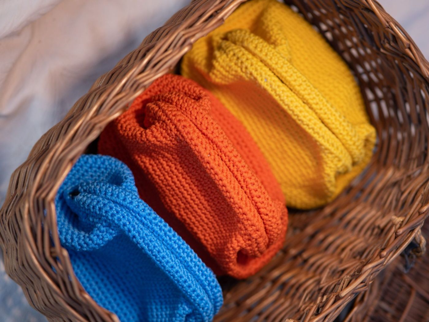 Capi in maglia colorati in un cesto di vimini