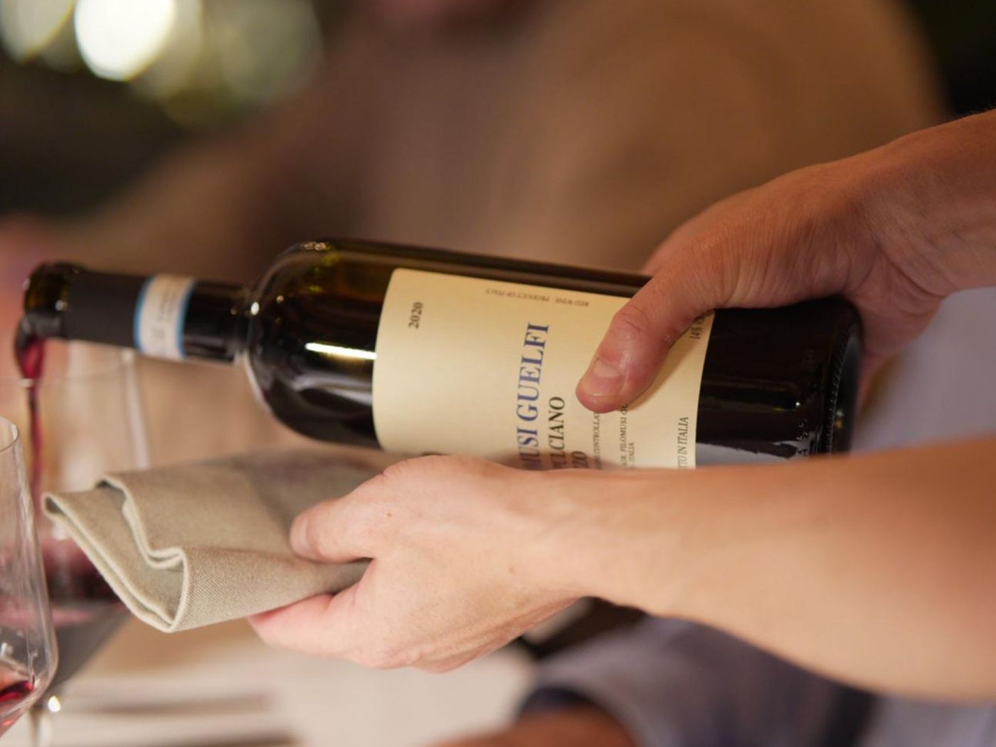 Sommelier che versa vino rosso in sala