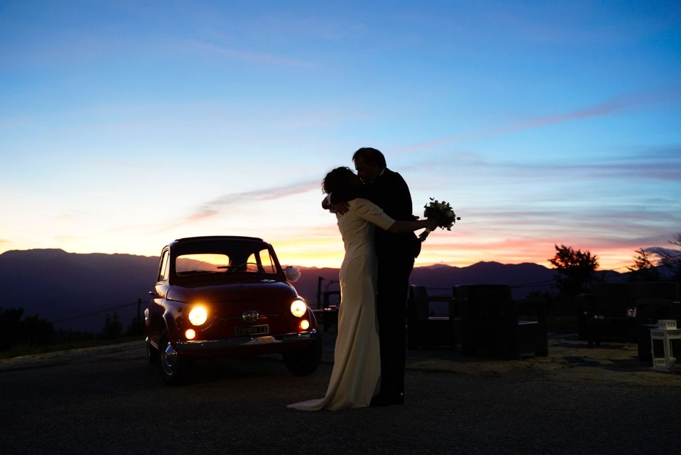 Sposi abbracciati al tramonto accanto a una 500 d'epoca